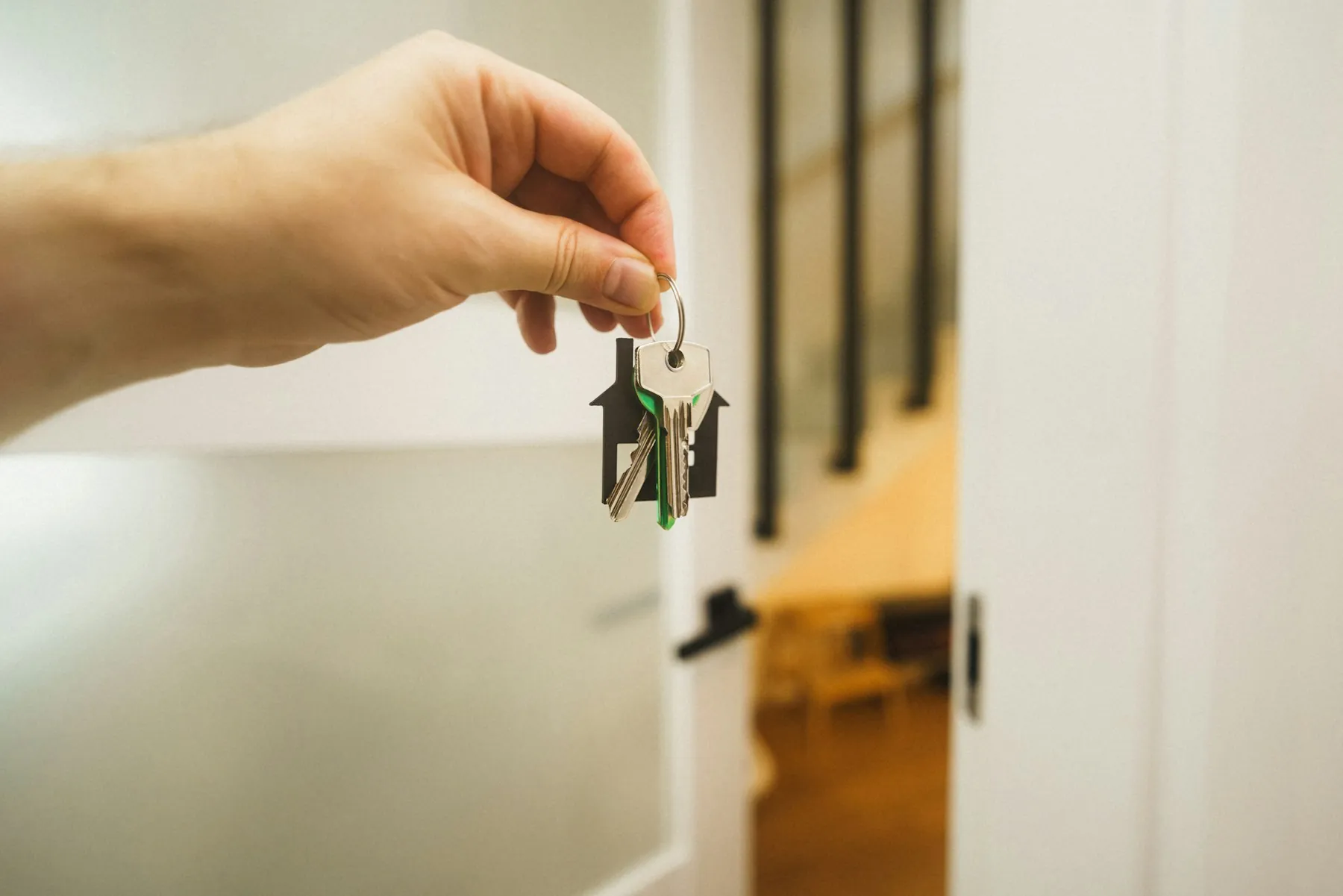Main tenant un trousseau de clés devant une porte d'entrée ouverte