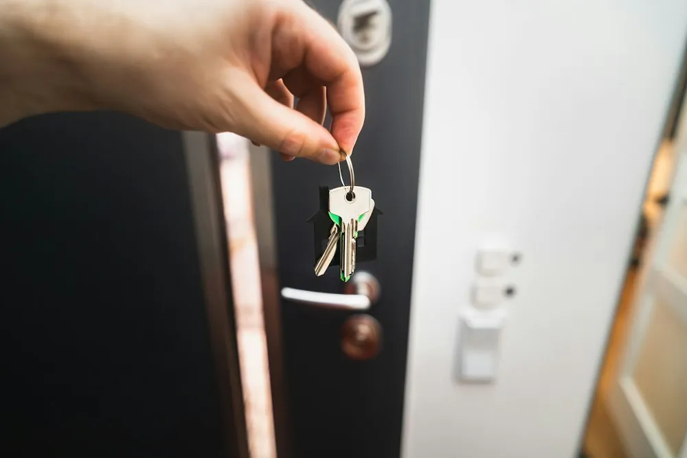 Main tenant des clés devant une porte d'entrée
